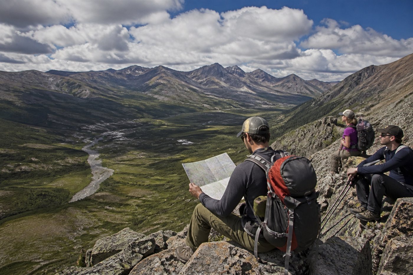 Backpacker studying a paper map at a mountain overlook